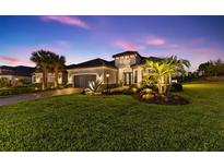 Elegant home exterior at twilight, featuring lush landscaping, palm trees, and a well-lit entrance at 4735 Trento Pl, Bradenton, FL 34211