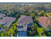 Beautiful aerial view of a tan two-story home with a tile roof and lush landscaping at 5670 Rock Dove Dr, Sarasota, FL 34241