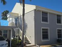 Two-story home featuring gray siding, white trim, and staircase leading to the entrance with a covered carport at 6142 7Th Ave W # 6142, Bradenton, FL 34209