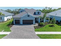 Beautiful single-Gathering home with a three-car garage, lush landscaping, and a brick paved driveway at 8046 Anthirium Loop, Sarasota, FL 34240