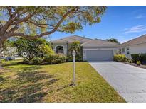 Charming single-story home with a well-manicured lawn and mature landscaping, including a palm tree at 8420 Sailing Loop, Lakewood Ranch, FL 34202