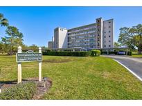 Well-manicured condo community with building sign, covered parking, and beautiful landscaping on a sunny day at 3660 Ironwood Cir # 205M, Bradenton, FL 34209