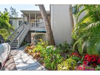 Inviting exterior view of a two-story building with lush landscaping, a staircase, and a peek of a car on the left at 1620 Boathouse Cir # 101, Sarasota, FL 34231