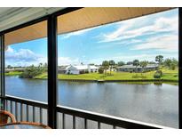 Scenic water view from screened lanai showcasing waterfront homes under a blue, partly cloudy sky at 1783 Lake Pl # 1783C, Venice, FL 34293