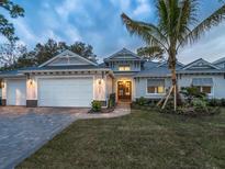 Charming one-story home featuring a three-car garage and a meticulously landscaped front yard with a palm tree at 5103 Windward Ave, Sarasota, FL 34242