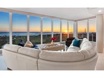 Bright living room features a modern white leather sofa with floor to ceiling windows offering gorgeous ocean views at 534 Beach Rd, Sarasota, FL 34242
