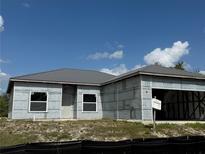 Exterior view of an unfinished one-story home with metal roof and an attached open garage at 6970 Beckwith Ave, North Port, FL 34291