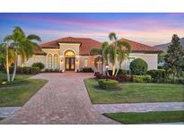 Beautiful home featuring a red tile roof, lush landscaping, and a paved driveway leading up to the entrance at 7469 Seacroft Cv, Lakewood Ranch, FL 34202
