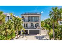 Stunning three-story home featuring a rooftop deck, balconies, and lush landscaping at 4101 4Th Ave, Holmes Beach, FL 34217
