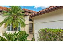 Charming home featuring lush landscaping, a tile roof, and a welcoming front entrance with a decorative window above the door at 4909 Clubview E Ct, Bradenton, FL 34203