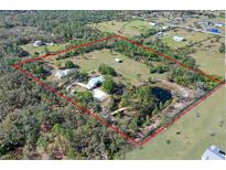 Expansive aerial view of estate with lush landscaping, pond, and horse pastures within property lines at 7108 229Th E St, Bradenton, FL 34211