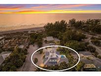Sunset aerial view of beach home with pool and rooftop deck encircled by mature landscaping at 112 50Th St, Holmes Beach, FL 34217