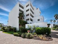 Bright white condominium building with lush landscaping under a blue sky at 1485 Gulf Of Mexico Dr # 205, Longboat Key, FL 34228
