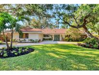 Inviting single-story home boasts lush landscaping, mature trees, and a circular driveway at 1610 S Lake Shore Dr, Sarasota, FL 34231