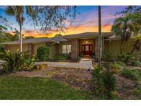 Charming home featuring a landscaped front yard, brick accents, and a welcoming red front door at sunset at 201 Eaglenook Way, Osprey, FL 34229