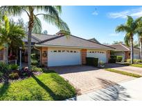 Charming villa with brick driveway and lush tropical landscaping, showcasing a welcoming curb appeal at 2123 Lynx Run, North Port, FL 34288