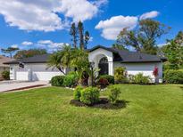 Beautifully landscaped front exterior with lush green lawn, mature palms, and elegant white facade at 5646 Country Lakes Dr, Sarasota, FL 34243