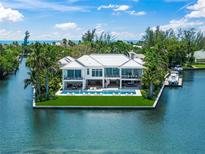 Stunning waterfront home with a modern design, lush landscaping, and a beautiful pool overlooking the water at 612 Juan Anasco Dr, Longboat Key, FL 34228