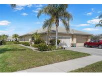 Well-maintained home exterior with lush landscaping, paver driveway, and attached two-car garage at 9847 Hawk Nest Ln, North Port, FL 34287
