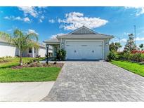 Charming single-story home with a paved driveway, lush landscaping, and a two-car garage under a blue sky at 995 Waterline Ct, Sarasota, FL 34240