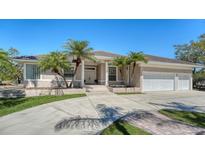 Charming home exterior featuring a three-car garage, tropical landscaping, and a circular driveway for easy access at 1030 Bahia Vista Ct, Sarasota, FL 34232