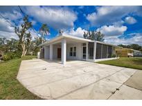 Single-story home featuring a covered parking area, a screened porch, and mature landscaping at 221 Laurel E Rd, Nokomis, FL 34275