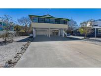 Stilt home featuring a large driveway and an enclosed lower level providing ample parking and storage space at 313 Magnolia Ave, Anna Maria, FL 34216