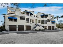 Stunning three-story building with modern architecture, blue awnings, and private garage spaces at 1900 Harbourside Dr # 102, Longboat Key, FL 34228