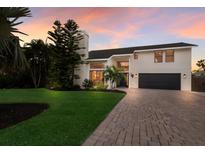 Beautiful two-story home featuring a brick driveway, well-manicured lawn, and mature landscaping at sunset at 1932 Baywood Ter, Sarasota, FL 34231