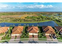Stunning aerial view of single-Gathering homes with tile roofs, set against a serene lake and lush green landscape at 24068 Canterwood Way, Venice, FL 34293