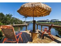 Relaxing waterfront dock featuring a tiki umbrella, chairs, and beautiful canal views at 2502 Larkspur Dr, Punta Gorda, FL 33950