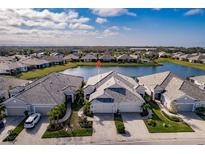 Stunning aerial view of the home with a tranquil lake backdrop, lush landscaping, and paver driveway at 2962 Trustee Ave, Sarasota, FL 34243