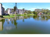 Scenic waterfront condo complex with lush landscaping and serene lake views on a clear, sunny day at 3664 Lake Bayshore Dr # K323, Bradenton, FL 34205