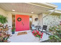 Inviting front entrance with a vibrant red door, decorative wreath and cozy seating area at 3880 Wilshire Cir # 28, Sarasota, FL 34238