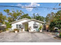 Charming single-story home with white stucco exterior, vibrant yellow door, and well-kept landscaping at 4487 Flatbush Ave, Sarasota, FL 34233