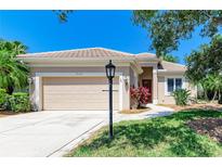 Well-manicured front yard with mature trees, a lamp post, and lush green grass creating a welcoming entrance at 9734 51St Terr E, Bradenton, FL 34211