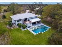 Aerial view of a modern two-story home with a backyard pool, lounge area, and outdoor dining at 15101 Rawls Rd, Sarasota, FL 34240