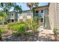 Condo building featuring lush landscaping, stairs leading to the entry door, and balconies in a beautiful setting at 1519 Pelican Point Dr # 288, Sarasota, FL 34231