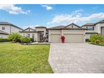 Beautiful single-story home featuring a tile roof, three-car garage, paver driveway and lush landscaping at 17519 Polo Trl, Lakewood Ranch, FL 34211