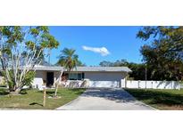 Charming single-story home with a well-manicured lawn, mature trees, and a paved driveway at 3013 Yarmouth W Dr, Bradenton, FL 34205