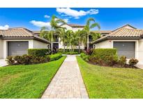 Beautifully landscaped condo building with manicured lawn, palm trees and paver walkway leading to the entrance at 5694 Palmer Cir # 204, Lakewood Ranch, FL 34211