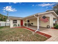 Charming single-story home featuring a covered parking area, red door, and an American flag at 5808 18Th W St # A & B, Bradenton, FL 34207