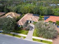 Stunning aerial view of a single-Gathering home with a tile roof, lush landscaping, and a paver driveway at 7533 Trillium Blvd, Sarasota, FL 34241