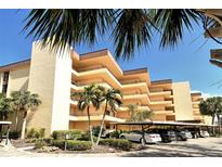 Multi-story condo building with palm trees, landscaping and covered parking spaces at 8779 Midnight Pass Rd # 406H, Sarasota, FL 34242