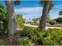 Landscaped front yard leading to a modern home with a circular driveway and lush greenery at 1909 Field Rd, Sarasota, FL 34231