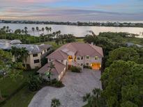 Waterfront home with lush landscaping, paver driveway, and serene sunset views over the bay at 1930 Bayshore Dr, Englewood, FL 34223