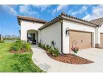 Charming home featuring a tile roof, stucco exterior, beautiful landscaping, and a two-car garage at 253 Tracino Ter, Nokomis, FL 34275