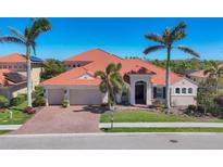 Charming single-Gathering home featuring lush landscaping, a brick driveway, and a classic tile roof at 261 Portofino Dr, North Venice, FL 34275