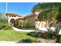 Charming two-story home featuring a tile roof, manicured lawn, and lush tropical landscaping at 4141 Entrada Ct, Sarasota, FL 34238