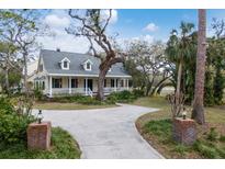 Charming yellow two-story home featuring a welcoming front porch and a long driveway at 4871 Hoyer Dr, Sarasota, FL 34241